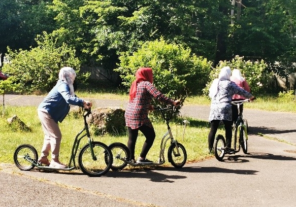 Vier Frauen Menschen fahren mit Rollern.