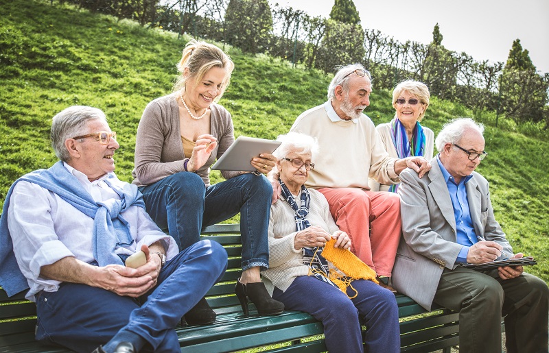 Sechs meist ältere Personen sitzen auf einer Bank.