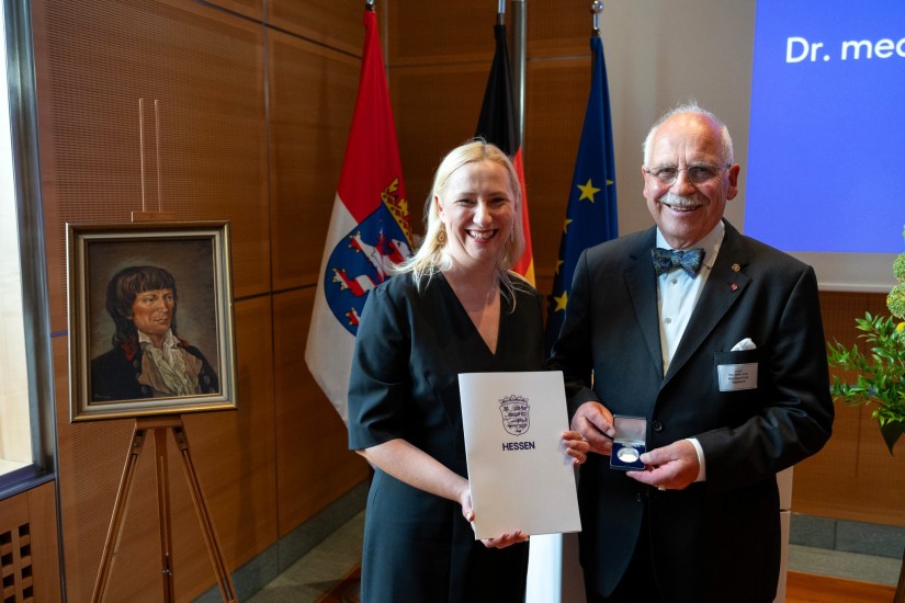 Staatsministerin Diana Stolz steht neben Dr. Gottfried von Knoblauch zu Hatzbach mit jeweils Urkunde und Medaille in den Händen