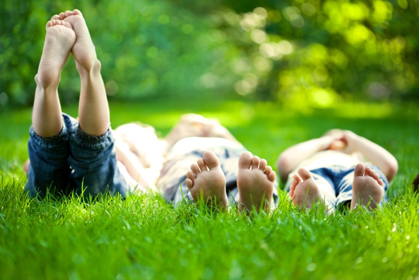 Drei Kinder liegen im Gras