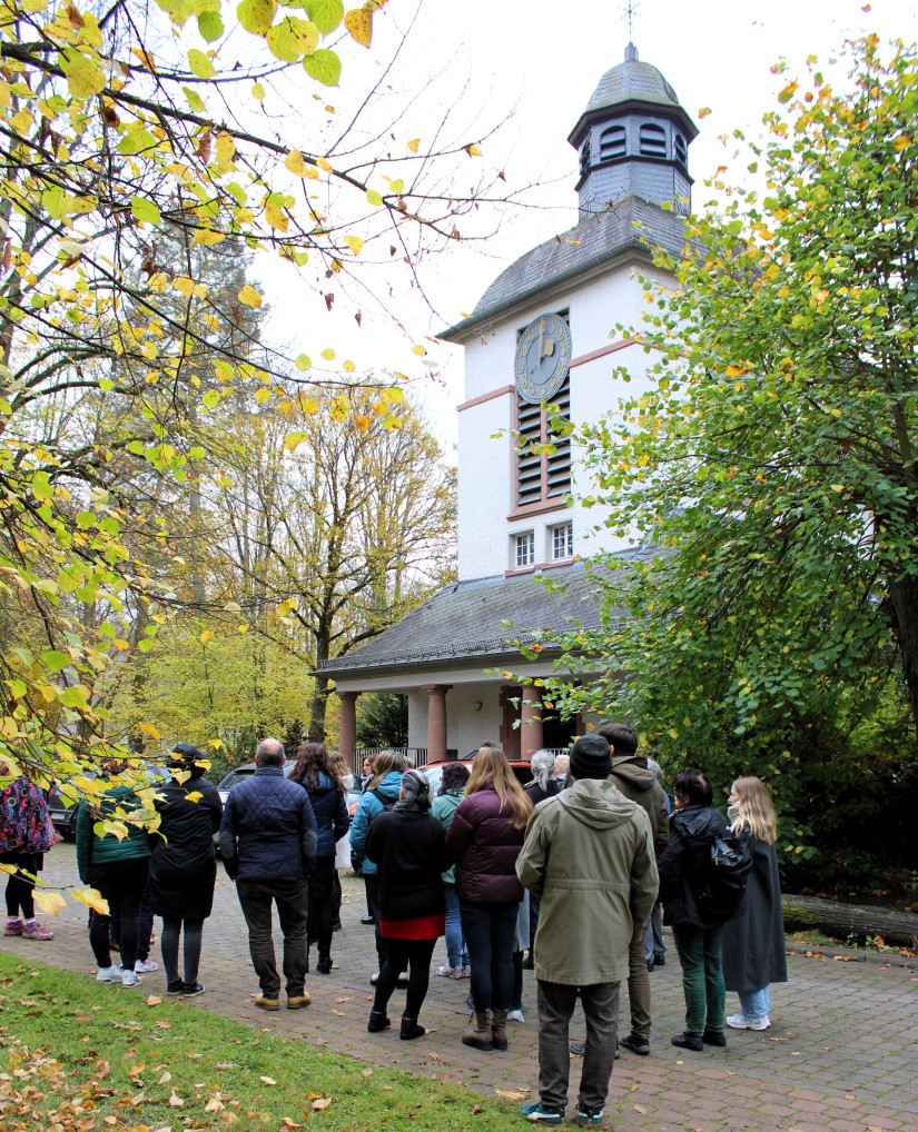 Personen stehen draußen und blicken auf eine Kapelle