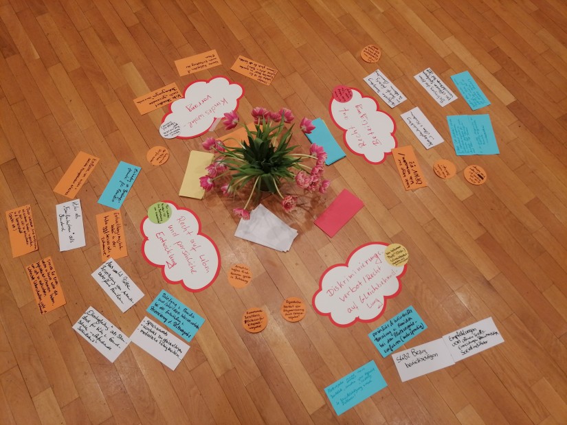 Auf dem Boden liegen Moderationskarten um eine Blumenvase herum erarbeitete Ergebnisse einer Gruppenarbeit.