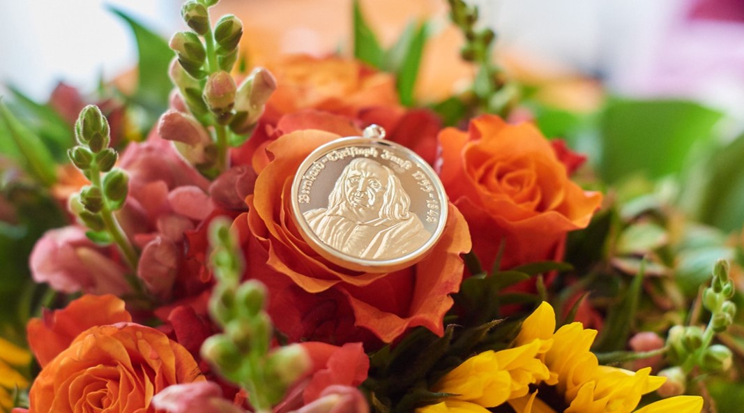 Bernhard-Christoph-Faust-Medaille, auf einerm Blumenbouquet liegend